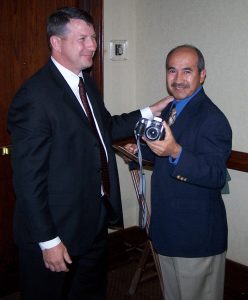 Thomas Escobar (right) accepts congratulations after having received a 2006 TMS Service Award for his exceptional contributions as Editor of TMS News.